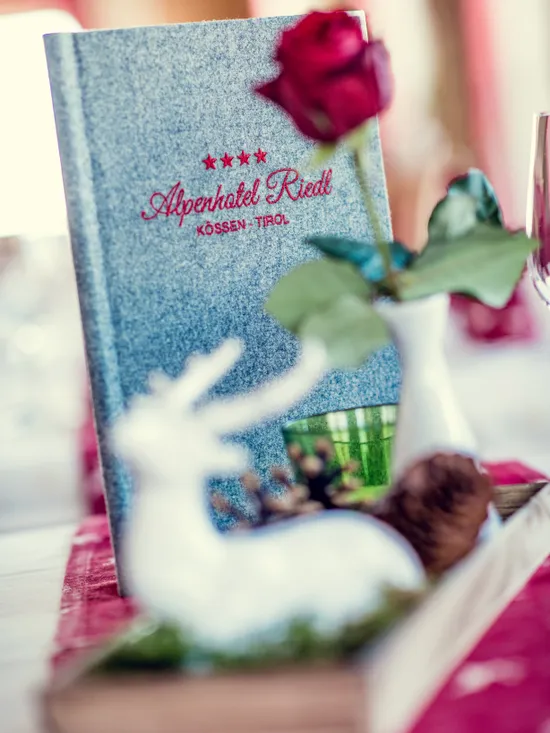 Speisekarte Alpenhotel Riedl mit roter Rose und festlicher Tischdeko in Kössen, Tirol